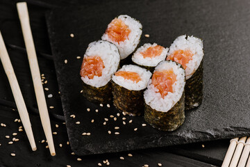 Appetizing sushi rolls with seafood on black background. Japanese food