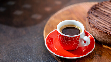 Classic chocolate cheesecake and a cup of coffee on a dark background. Homemade baking.