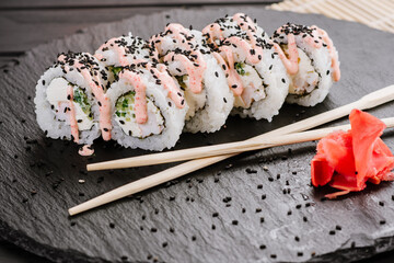 Delicious fresh sushi rolls with seafood and cream cheese on black background