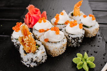 Fresh sushi rolls with srimp and red caviar on black background