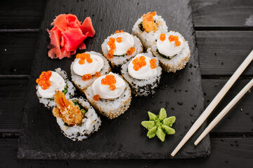 Fresh sushi rolls with srimp and red caviar on black background