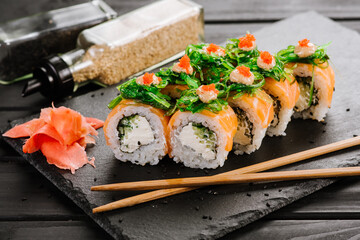 Tasty fresh sushi rolls with salmon on black background