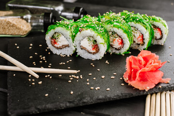 Sushi rolls with seafood and Chuka salad on black background