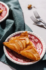 Slices of Homemade French Apple Tart or Pie on plates on light concrete background