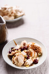 Not traditional Eton mess. Meringue, pistachio, cherry and caramel sauce dessert. Selective focus
