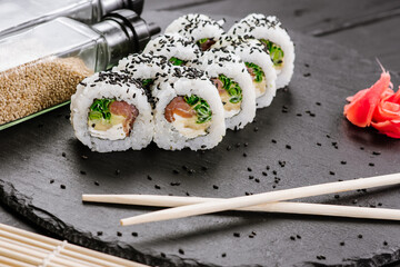 Appetizing sushi rolls with seafood on black background. Japanese food