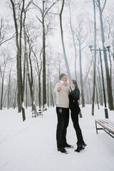 A man and a woman with sparklers on the background of a snow-covered forest in a snowfall