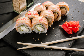 Tasty fresh sushi rolls with salmon on black background
