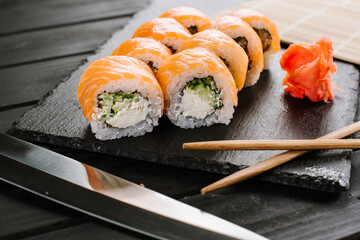 Tasty fresh sushi rolls with salmon on black background