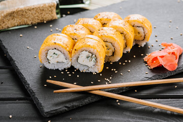Sushi rolls with cheddar cheese on black background