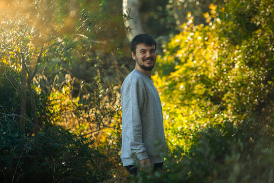 
young man among branches in the forest with sunlight