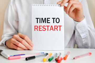 A sheet of paper with text TIME TO RESTART, multicolored markers on a white table. Business and...