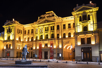 Fototapeta na wymiar Lithuanian National Philharmonic in Vilnius, night view with snow and monument of Jonas Basanavičius