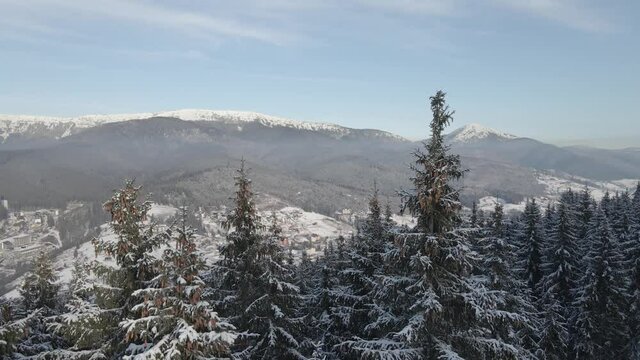 Drone flight above the snow-covered mountains and winter forest. Pine trees. Winter wonderland. Mountains drone aerial footage. Epic view. Winter mountain view from above. Travel. Snow peak. 