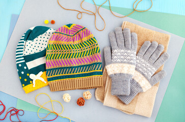 Bright hats and gloves for autumn and winter. Clothes for the cold seasons in the form of hats and gloves. Knitted hats and gloves on a colorful background.