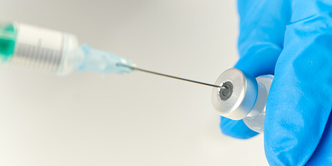 Fototapeta premium doctor hands injecting a syringe needle into a small bottle with a vaccine or drug assign virus or flu.