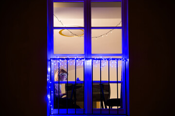 Blond hair girl near the window working at home at the desk in the evening or night, working or...