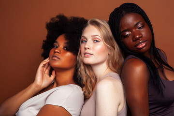 Obraz premium young pretty caucasian, afro, scandinavian woman posing cheerful together on brown background, lifestyle diverse nationality people concept