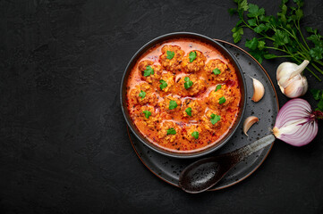 Sulu Kofte in black bowl on dark slate table top. Turkish cuisine soup dish with beef meatballs and gravy. Traditional food. Top view. Copy space