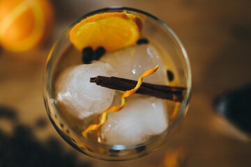 Coctel de ron con naranja y aromáticos. Copa de alcohol sobre mesa. Bebida espirituosa. Canela, café y naranja.