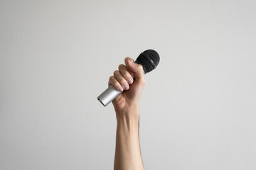 Hand holding a wireless microphone on a white background