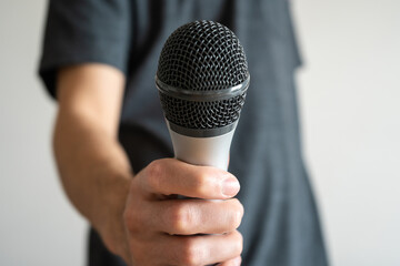 Young man passing the microphone to another person. Close up.