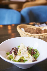 Kidney beans health salad. Dark table and white plate. Cafe menu. Green leaves and cheese fitness dinner. Organic vegetable diet. Black bread bowl. Vegan product. Fast eat.