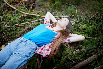 Beautiful young brunette woman with long hair in a forest pines and firs on a summer day