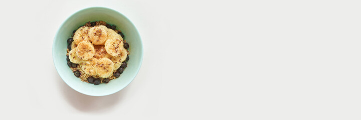 Healthy breakfast. Top view. Oatmeal with banana and flax seeds at bowl. Berry in plate. Organic meal recipe. Vegan cook. Minimalism granola. Hot porrigde with fruit. Banner, copyspace