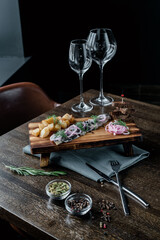 Board with snacks and glass glasses served on the table on a black background
