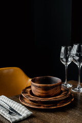 Wooden plates and glass goblets served on table on black background