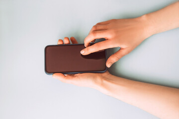 Woman's hand is pressing the button on smart phone screen on a light blue background. Mock up
