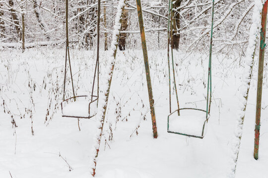 Stara, metalowa huśtawka ustawiona w środku lasu w zimowej śnieżej białej scenerii