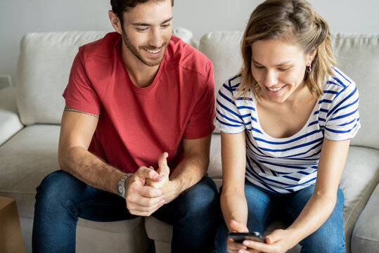 Young couple using smartphone in their new house