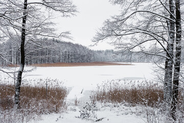Stara kładka nad mazurskim jeziorem w zimowej śnieżnej scenerii