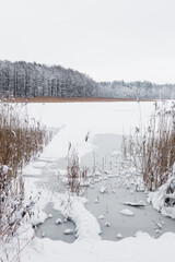 Stara kładka nad mazurskim jeziorem w zimowej śnieżnej scenerii