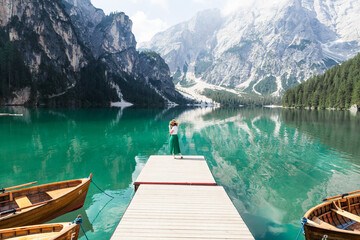 Fototapeta premium the girl standing on the dock of the lake Braies, Italy, minimalism