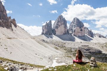 girl sitting on the edge of a cliff and looking at the mountains, italy Tre cime di Lovaredo