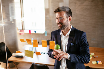 Businessman in conference room use sticky notes on glass wall. Handsome businessman making a business plan..