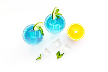 Blue beverage, iced alcohol cocktail drink with lime and mint, top view