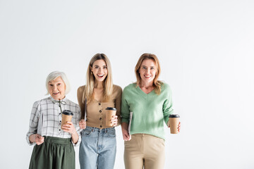 Obraz premium three generation of excited women holding newspapers and paper cups isolated on white