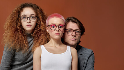 Front portrait of three youngs caucasian stylish models in casual clothes, wear eyeglasses, over...