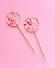 Two transparent lollipops on a pink background.