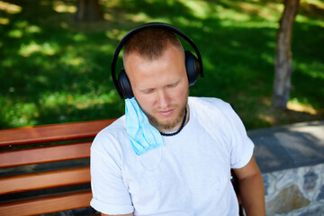 Man listening music with headphone, wearing protective mask outdoor