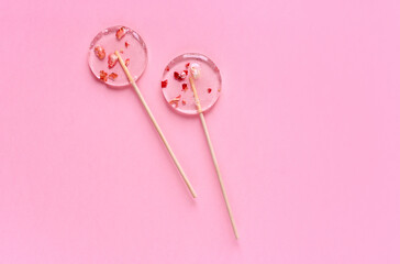 Two transparent lollipops on a pink background.