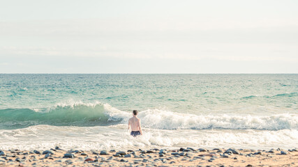 Athletic young man walking on a beach in Gran Canaria during Covid after a swim in Atlantic Ocean