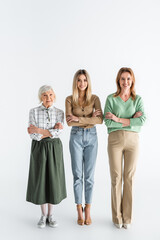 Obraz premium full length of three generation of happy women smiling while standing with crossed arms on white