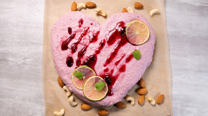 Top view of heart shaped vegan raw cake with strawberry and cashew nuts