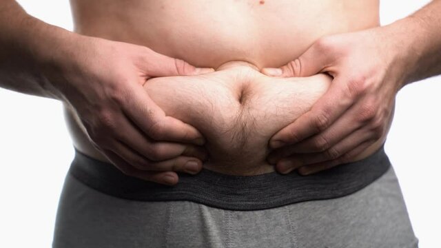 Close-up, male stomach, overweight. Young man with a naked fat belly shakes fat folds on his stomach, obesity, health, beer belly