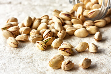 Organic pistachio nuts scattered on a light stone background. Copy space. Selective focus.